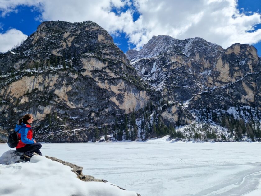 2 días en los Dolomitas en abril: itinerario perfecto y guía del clima braies on a rock Disfrutando de las vistas del lago de Braies nevado, sentada sobre una enorme roca, en los Dolomitas