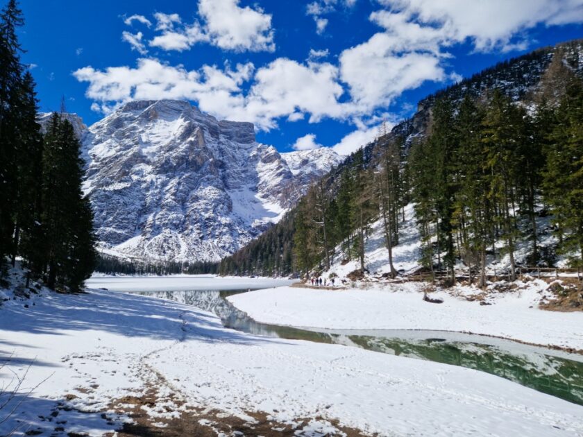2 días en los Dolomitas en abril: itinerario perfecto y guía del clima braies other side of river El río y el lago de Braies vistos desde el lado del puente, con mucha nieve y aguas turquesa, en los Dolomitas en abril
