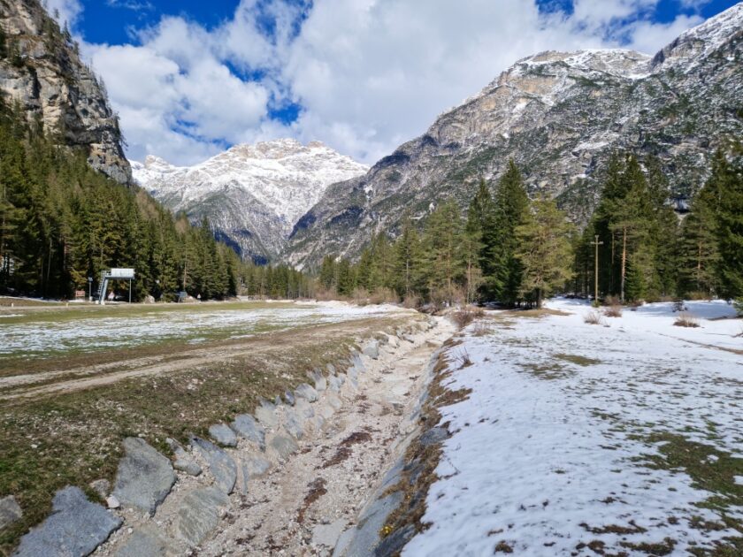 2 días en los Dolomitas en abril: itinerario perfecto y guía del clima dry river Un lecho de río seco en abril en los Dolomitas, con nieve y montañas nevadas alrededor, Italia
