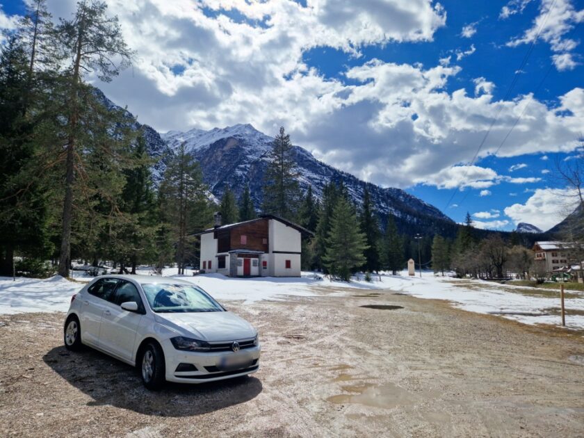 2 días en los Dolomitas en abril: itinerario perfecto y guía del clima good random parking stop Un auto estacionado en un estacionamiento mojado y con nieve, rodeado de montañas, en los Dolomitas, Italia