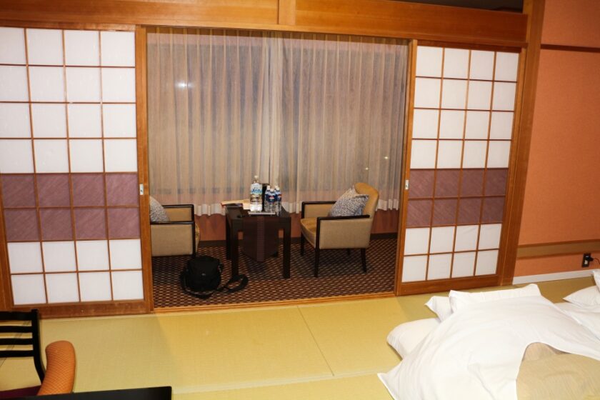 La experiencia de un ryokan en Japón: por qué no te la puedes perder relax area gora ryokan Zona de descanso de un ryokan en Japón con sillas, mesa y agua, suelo de tatami y futones a la vista