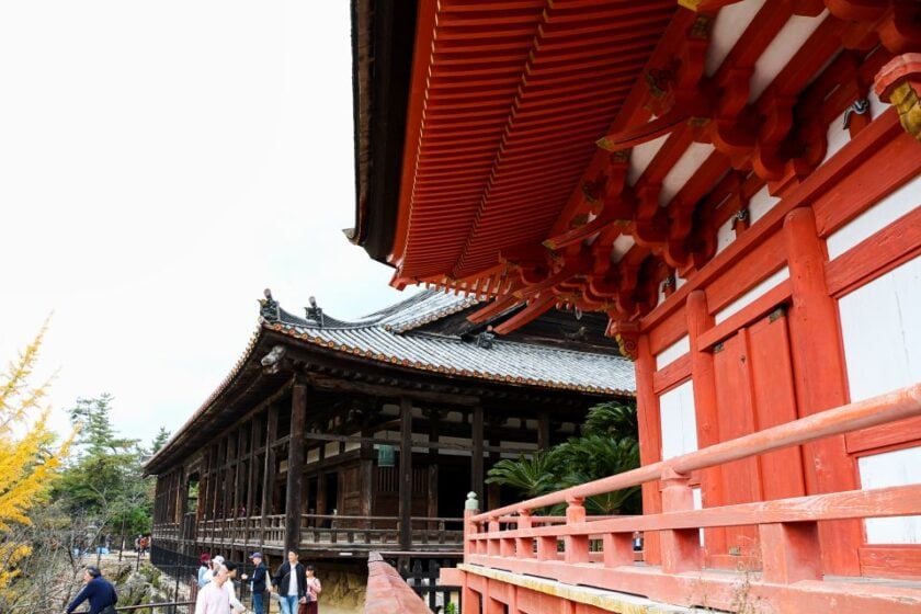 Japón en noviembre: itinerario de 10 días en fotos Miyajima shrine japan Un edificio rojo brillante en primer plano y un templo de madera oscura al fondo, en Miyajima, Japón